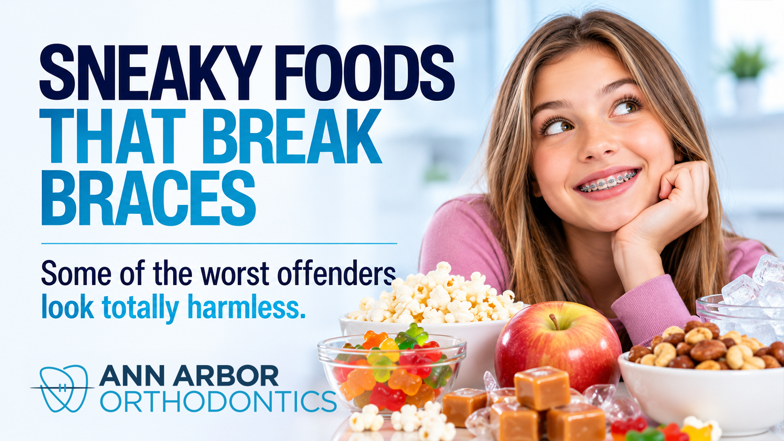 A smiling teen with braces rests her chin on her hand behind bowls of popcorn, gummy candy, caramels, mixed nuts, ice, and a red apple, all risky foods for braces.